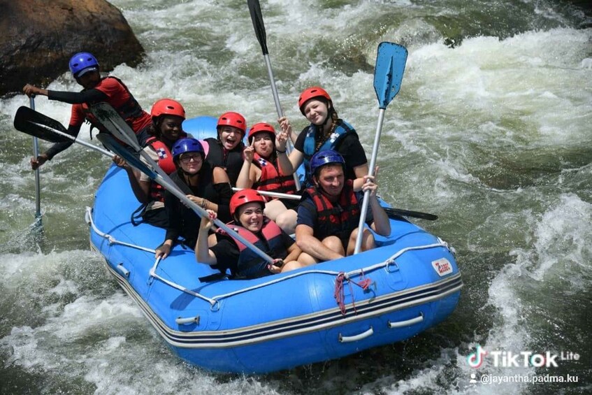 A group of people in a blue raft navigating a river with rapids. 1