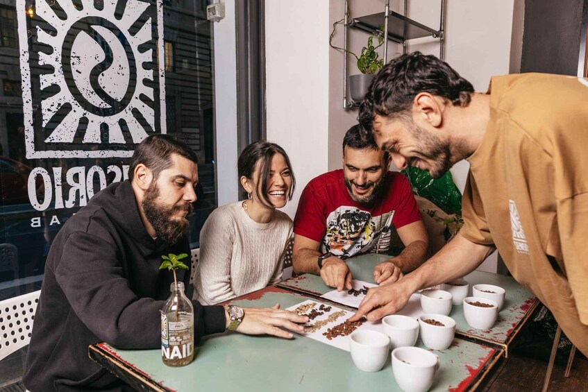 Four people at a table with bowls of food, a bottle of nail polish, and a sign with a sun symbol. 1