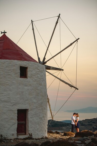 A white building with a red roof and a windmill. 5