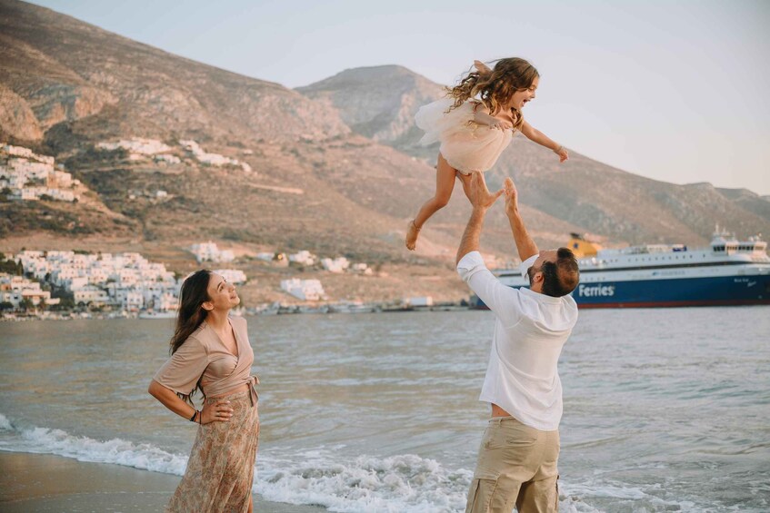 A coastal scene with a ship named 'Ferries' in the background, a person lifting a child, and a woman standing on the beach. 2