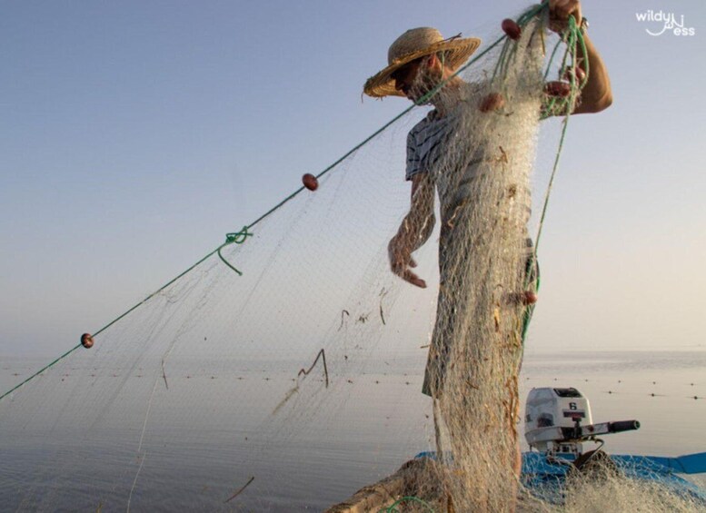 A person fishing with a net and a boat. 4