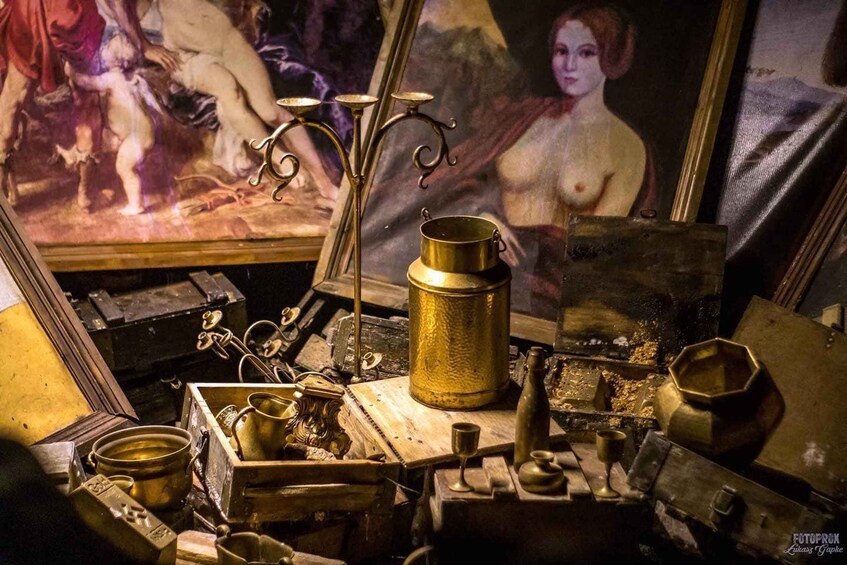 A cluttered antique workshop with brass items, a painting, and a candelabra. 5