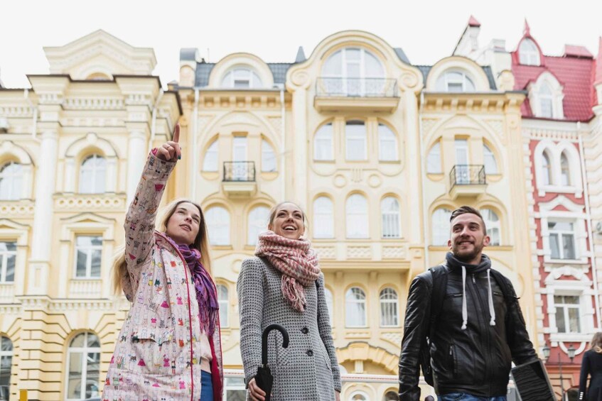 Three people standing in front of a historic building with ornate architecture. 5
