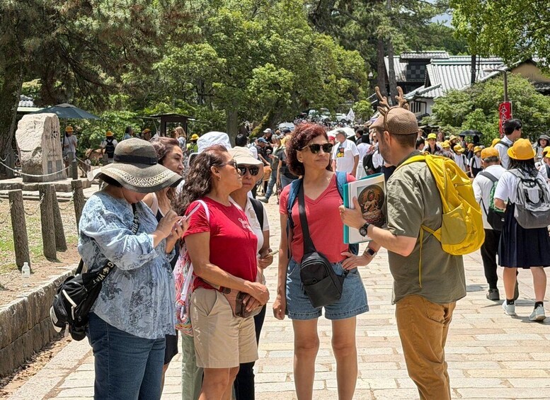 A group of tourists at a historical site with traditional architecture in the background. 2