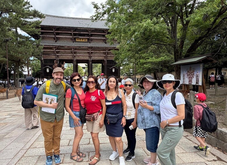 A group of people standing in front of a traditional Japanese building with a tiled roof and wooden structure. 1