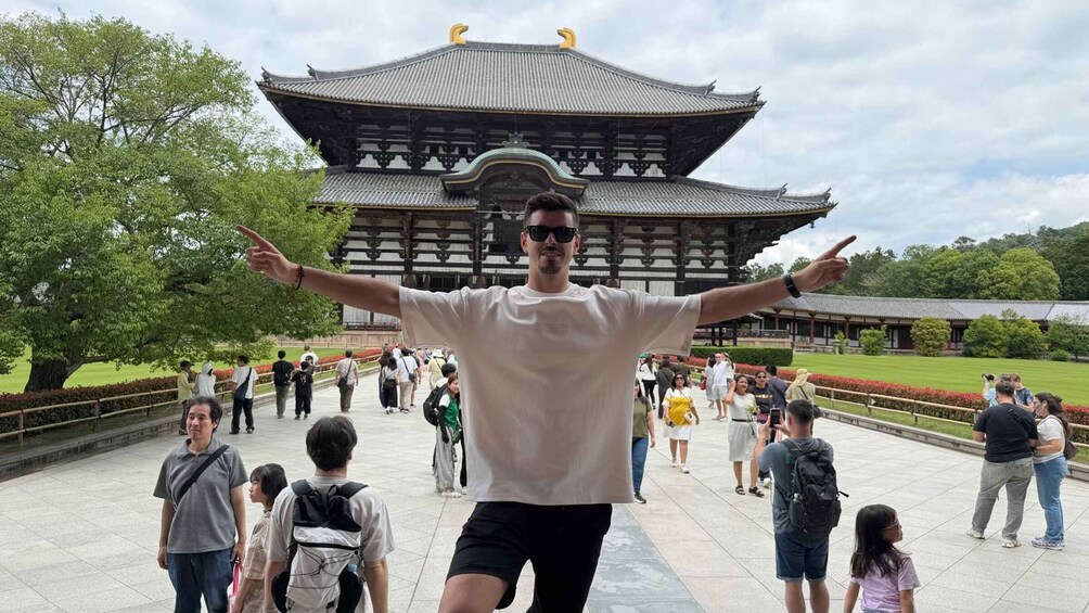 A person pointing towards a traditional multi-tiered building with a tiled roof and ornate details. 3