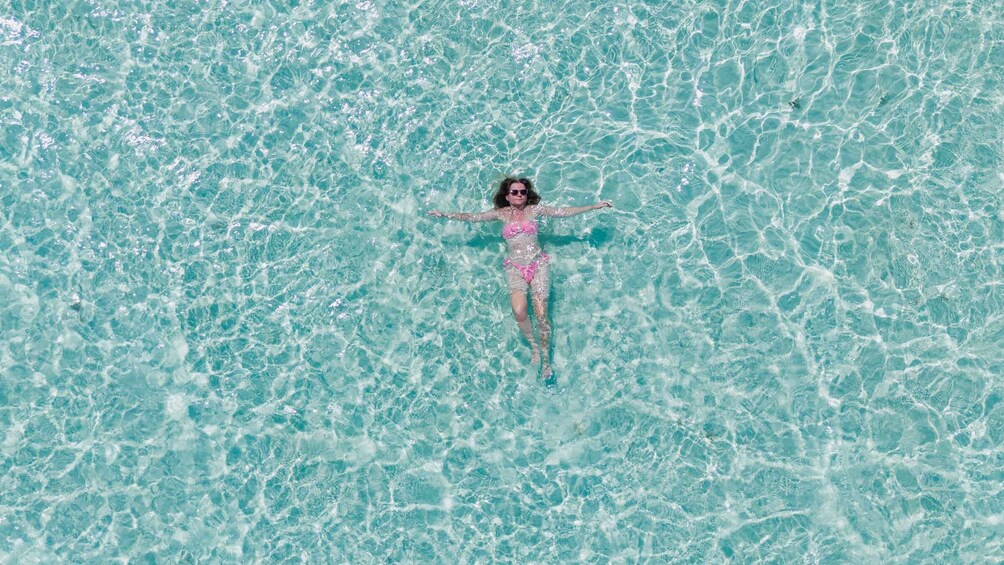 A person floating in clear turquoise water. 1