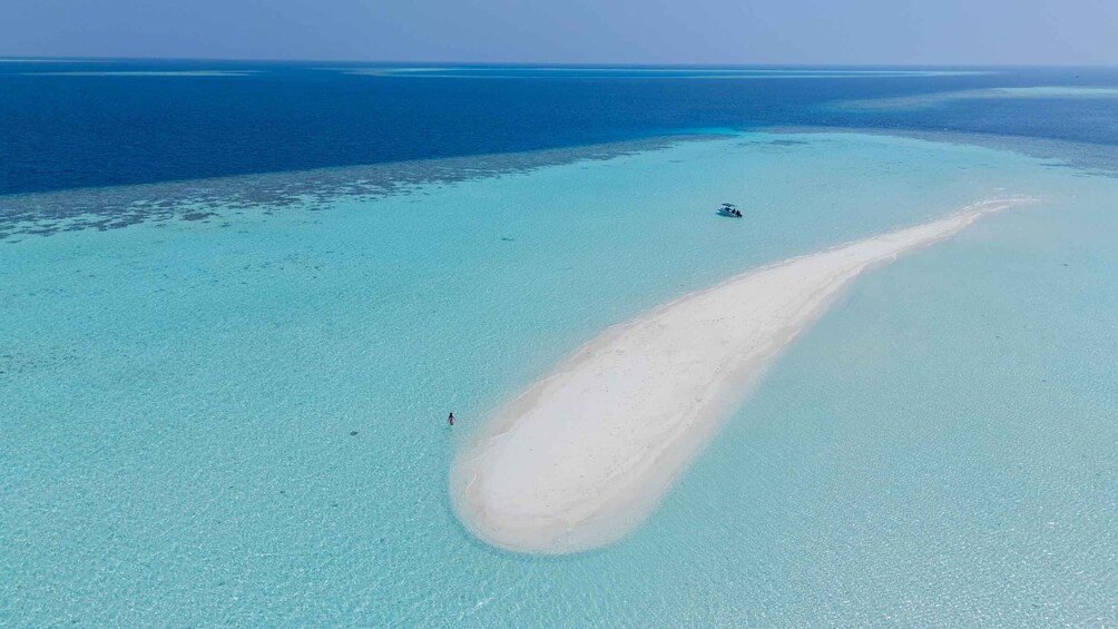 A clear turquoise sea with a sandy beach and a boat in the distance. 3