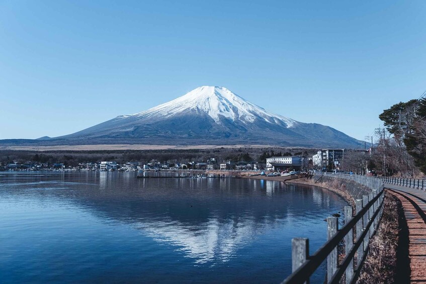 A snow-capped mountain, a calm lake, and a town with buildings along the shore. 5
