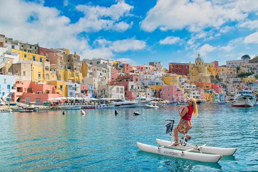 A person on a paddleboard in a vibrant coastal town with colorful buildings and boats in the water. 1