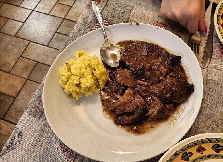 A plate with a serving of meat and mashed potatoes on a tablecloth. 5
