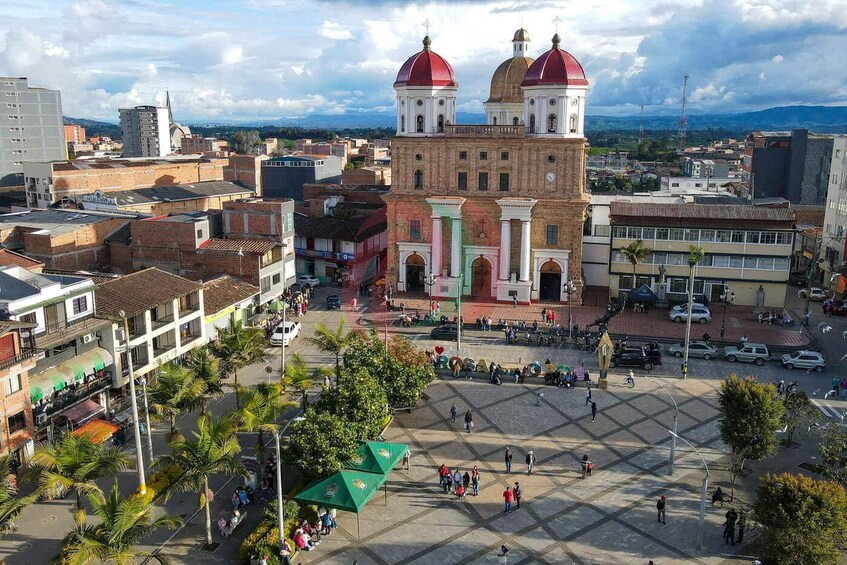A city square with a prominent church with red domes, surrounded by buildings and palm trees. 4