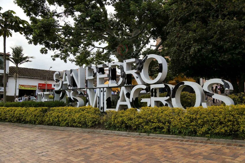 A large outdoor sign with the text 'SÃO PEDRO SÃO PAULO' surrounded by greenery and a paved walkway. 5