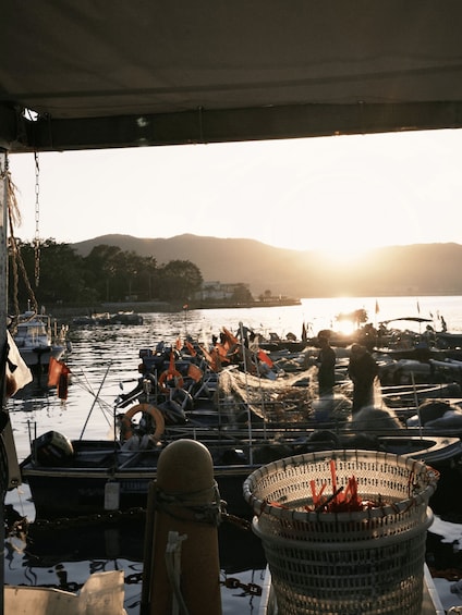 A harbor at sunset with boats docked and people working. 3