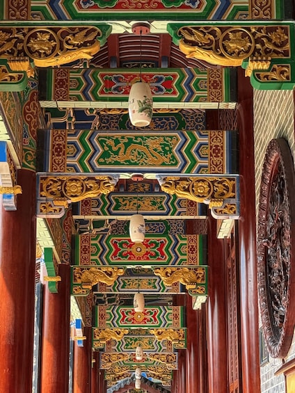 A corridor with ornate, colorful ceiling decorations and traditional architectural elements. 4