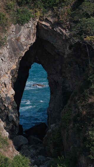 A natural rock arch formation with a view of the ocean through it. 1