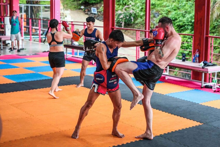 A martial arts training session with participants wearing protective gear on a colorful mat. 1