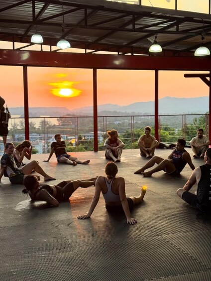 A group of people sitting on mats outdoors during sunset. 5