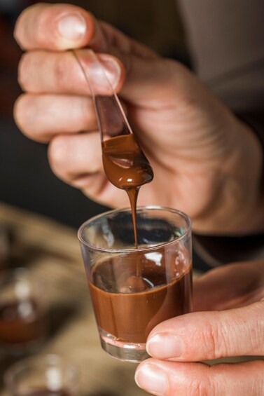 A person pouring a brown liquid into a clear glass. 2