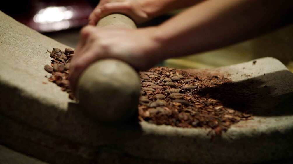 Hands using a mortar and pestle on coffee beans. 4