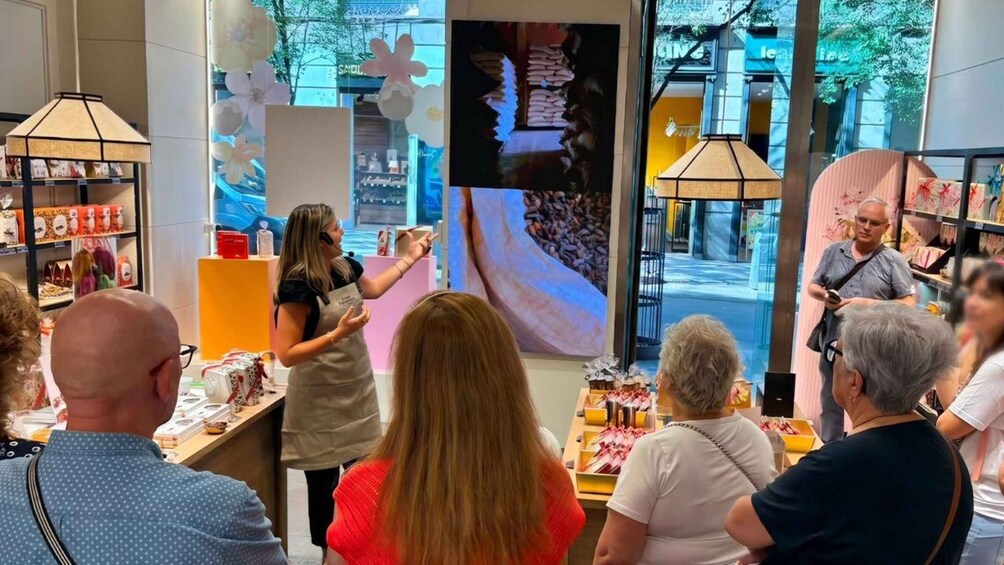 A group of people inside a store with a large digital display and shelves with products. 1