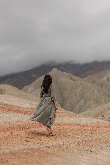 A person walking on a rocky terrain with mountains in the background. 2