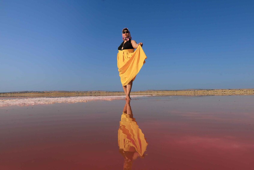 A person standing on a reflective surface with a clear sky. 1
