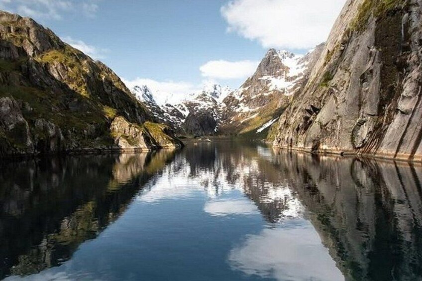 A calm lake surrounded by mountains with snow-capped peaks. 2