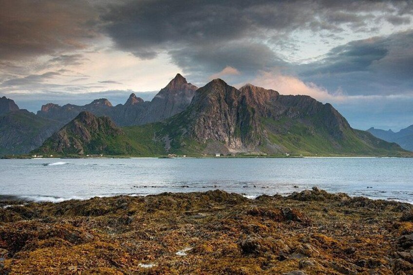 A coastal landscape with rugged mountains, a rocky shoreline, and a calm sea. 3