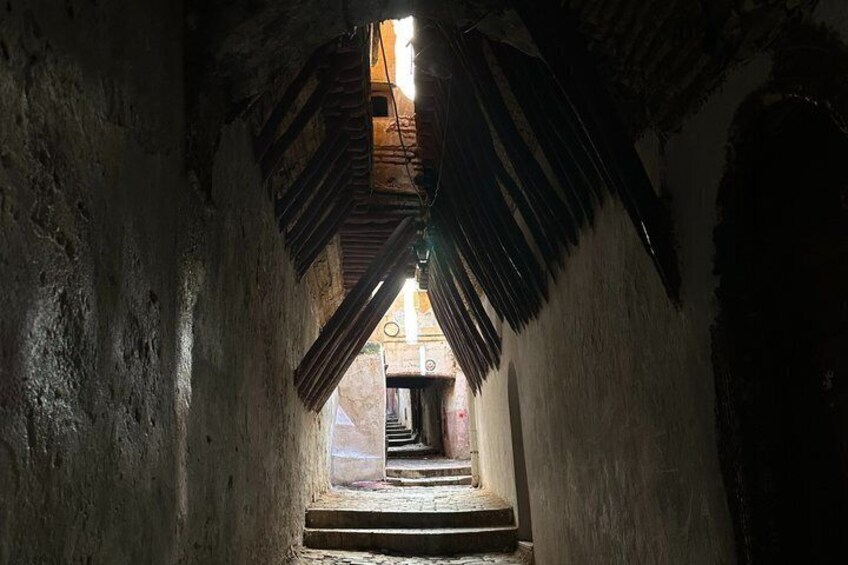 A narrow passageway with a wooden ceiling and a view of a building through a window. 3