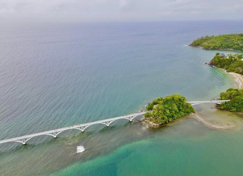 A white bridge over turquoise waters, surrounded by lush greenery and a small island. 5
