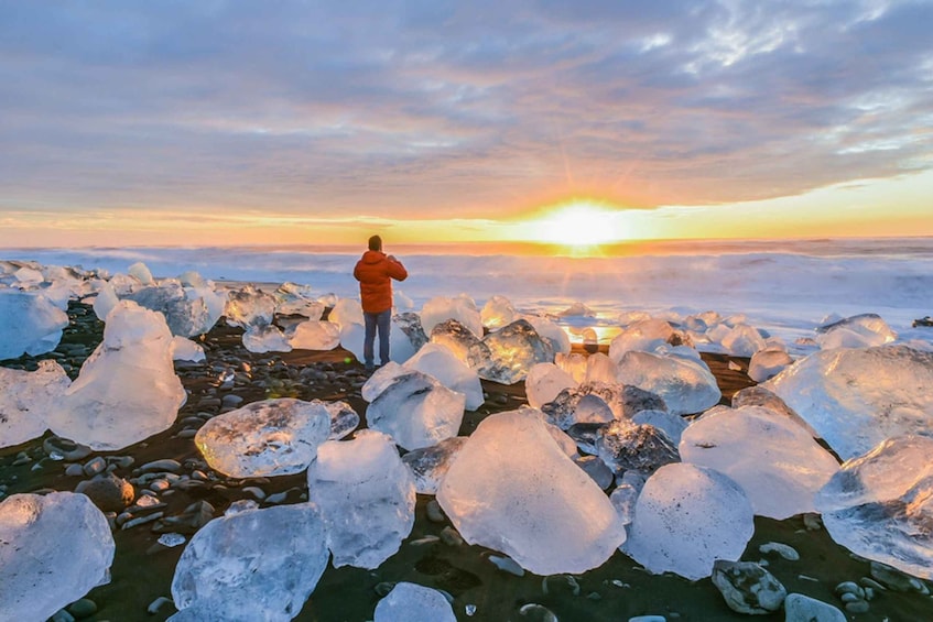 A person standing on ice with the sun setting in the background. 1