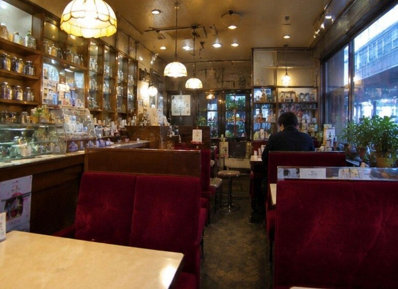 A restaurant interior with booths, tables, hanging lights, and a counter with jars. 5