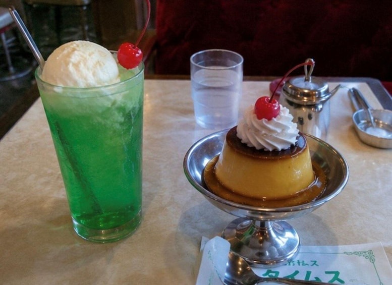 A dessert with whipped cream and cherries on a plate, next to a green drink with a cherry on the rim. 4