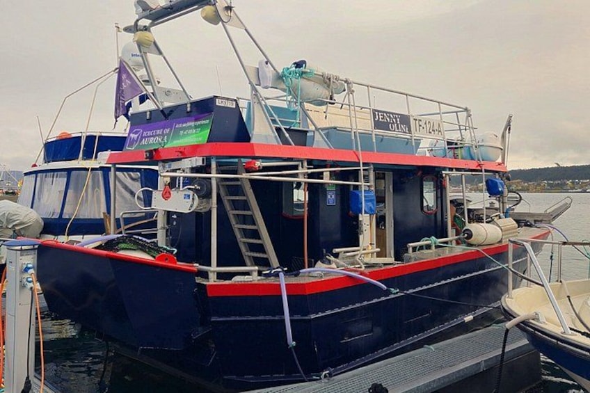 A fishing boat docked at a marina with a ladder, winches, and a name sign. 3