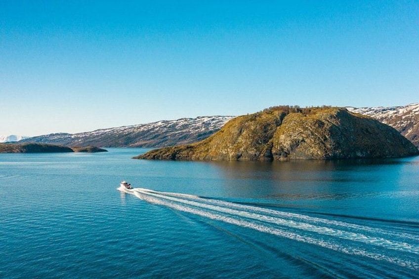 A boat speeding across a calm lake with a rocky island in the background. 4