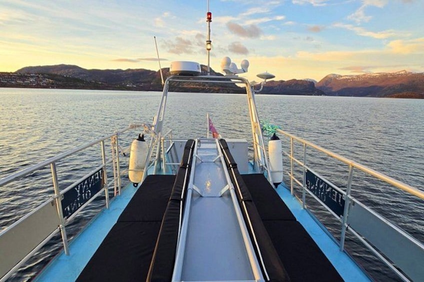 A boat deck with a wakeboard ramp, railings, and a view of a calm lake with mountains in the distance. 2