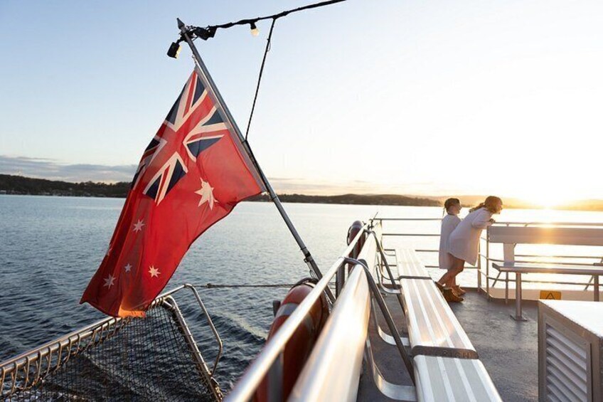 A boat with a flag, a person leaning on a railing, and a sunset in the background. 2