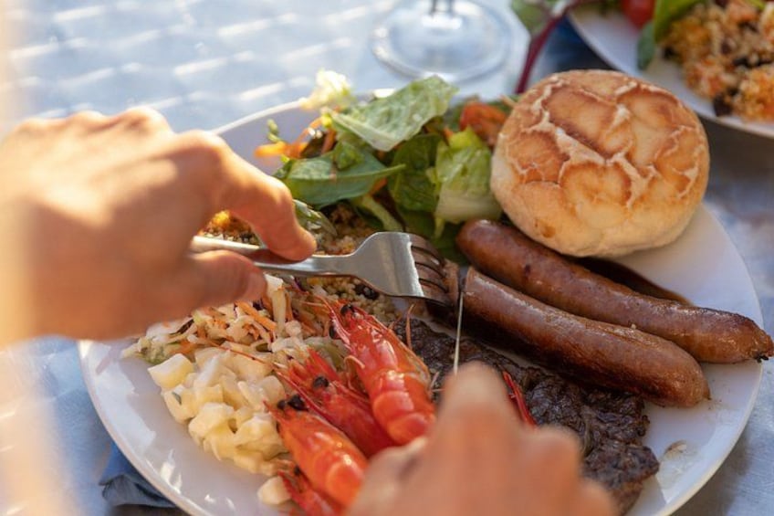 A plate with food including sausages, shrimp, and a salad. 2