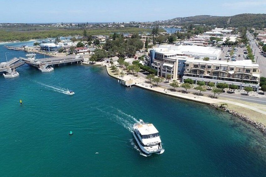 A cruise ship in a marina with buildings and a bridge in the background. 1