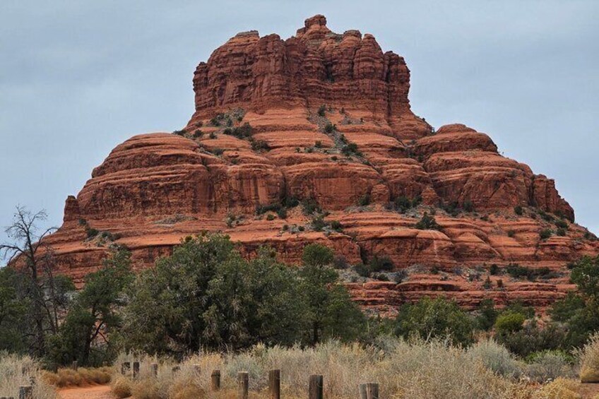 A large red rock formation with sparse vegetation in the foreground. 4