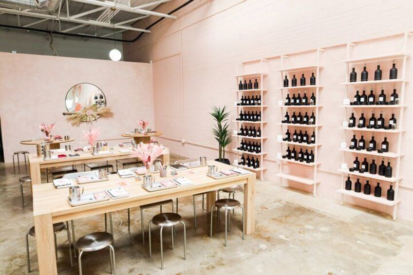 A salon interior with a wooden table, chairs, and shelves of black bottles. 2