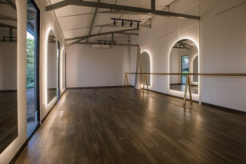An empty art gallery with wooden floors, large windows, and arched ceilings. 2