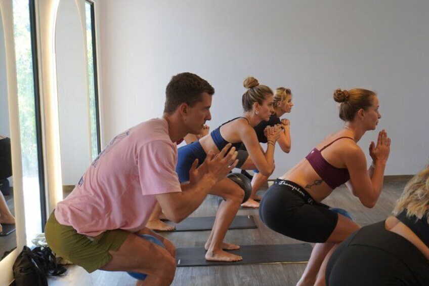 A group of people in a squat position, likely during a workout or exercise class. 5