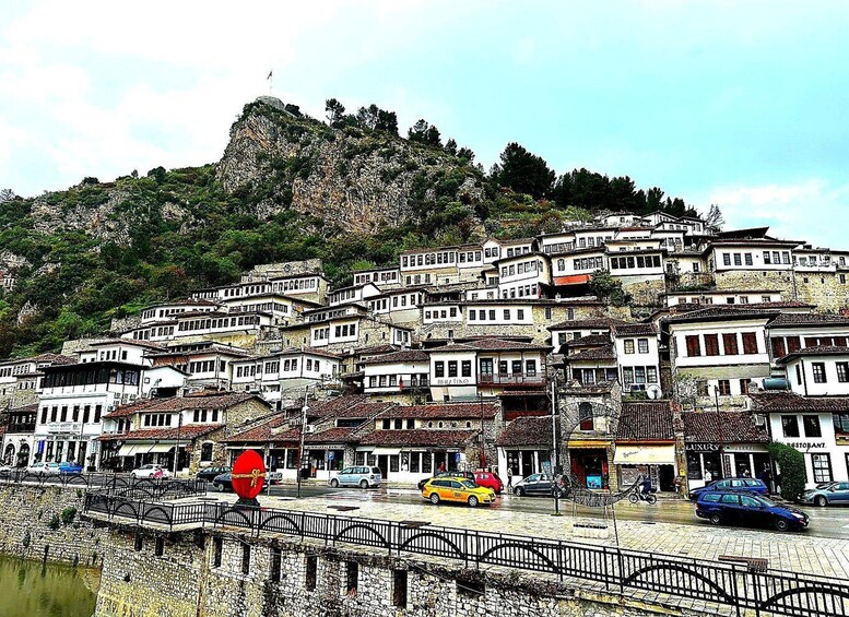 A hillside town with white buildings, a river, and a bridge. 3