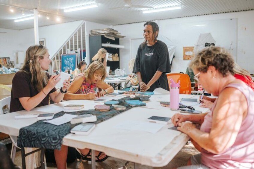 A group of people engaged in a craft activity at a table with various materials and tools. 2