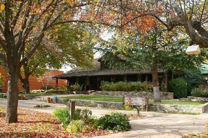 A building with a sign reading 'Governor's Mansion' surrounded by trees and a well-maintained lawn. 2