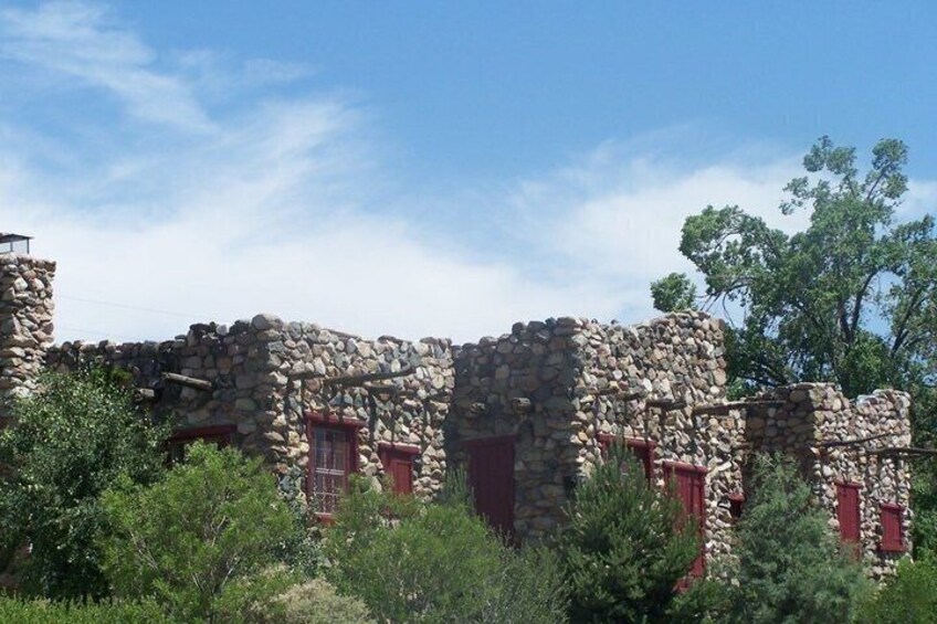 A stone building with red window shutters, surrounded by greenery. 5