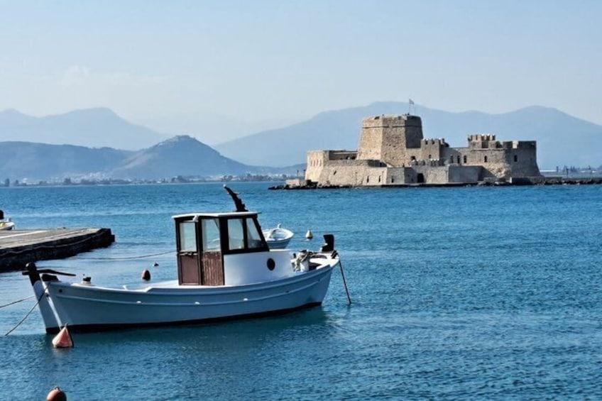 A boat docked near a historic castle by the sea. 1