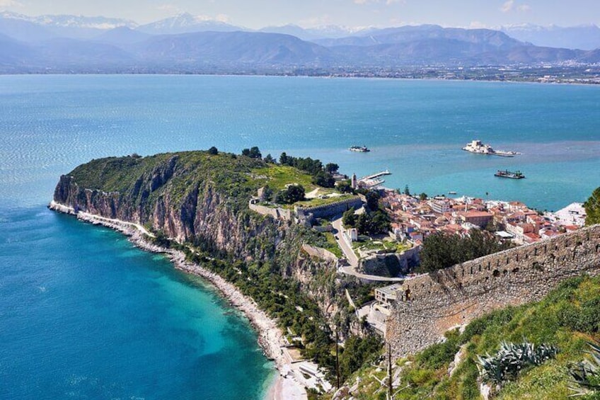 A coastal town with a fortified wall, a beach, and a mountainous backdrop. 3